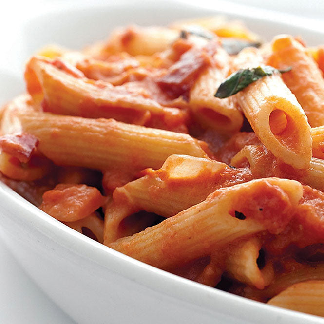 Close up of a white bowl filled with penne pasta topped with Chunky Tomato Sauce