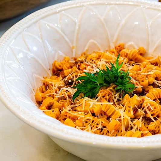 Close up of a white bowl filled with Dagostino Crawfish Pasta and a light red-colored Sauce.
