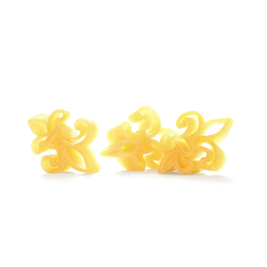 Close up of three pieces of dried Dagostino Fleur de Lis Pasta against a white background.