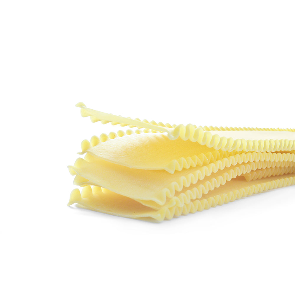 Close up of a stack of dried lasagna pasta sheets against a white background.