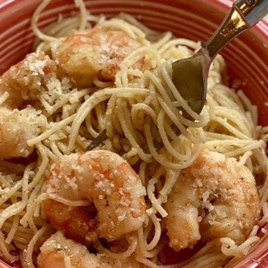 Close up of a fork digging into a bowl of Dagostino Vermicelli Pasta with Lemon Butter Shrimp.