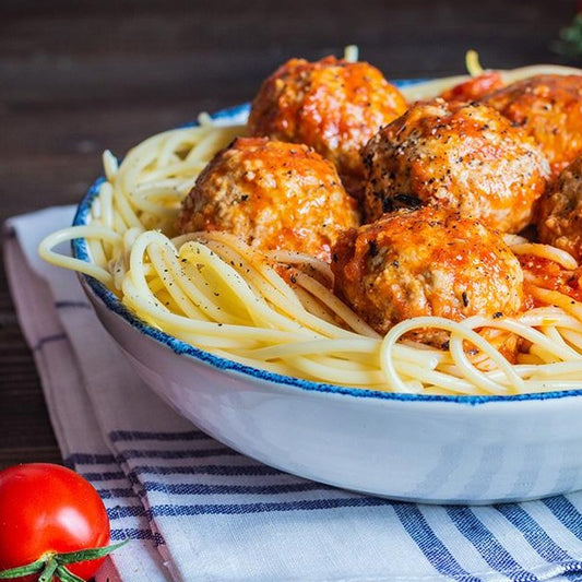 Close up of a white bowl filled with Dagostino Spaghetti and Meatballs in tomato sauce.